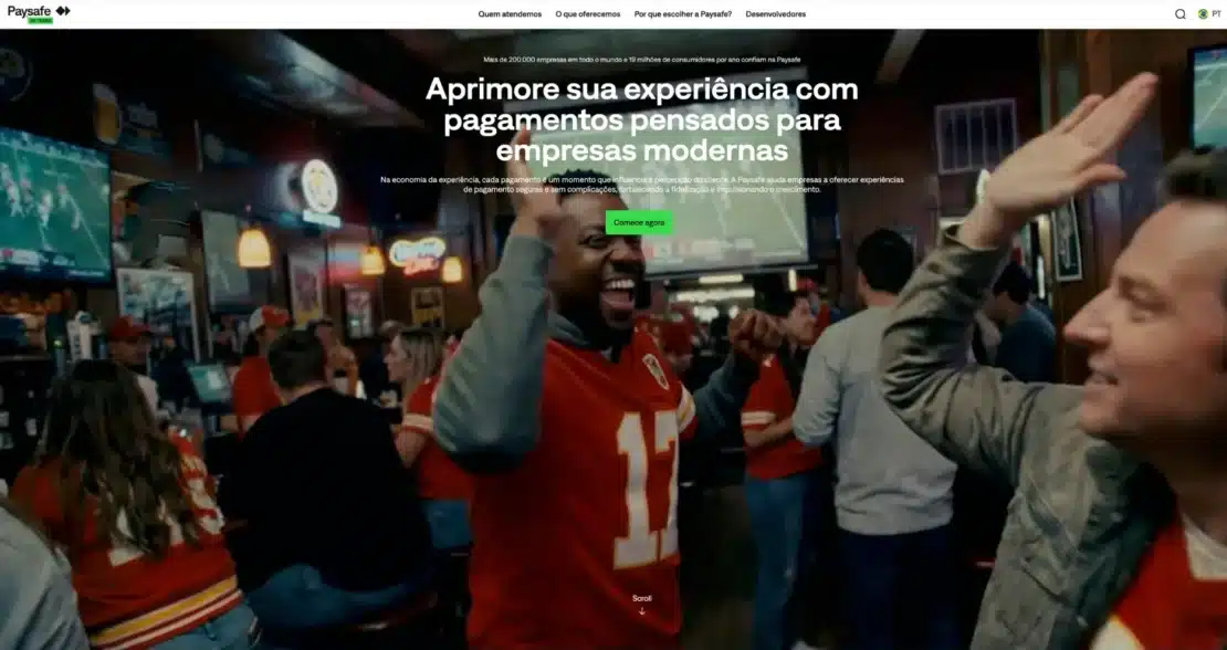 Página inicial da Paysafe em português com o título Aprimore sua experiência com pagamentos pensados para empresas modernas sobre a foto de torcedores comemorando em um bar